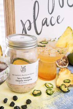 two jars filled with different types of food on top of a table next to fruit