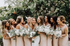 a group of women standing next to each other with bouquets in their hands and smiling