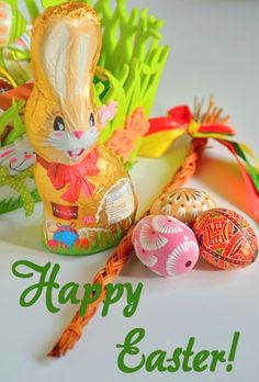 a happy easter card with an image of a bunny, eggs and carrots on the table