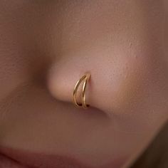 a woman's nose with two gold rings on it