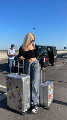 a woman with two suitcases standing in the parking lot