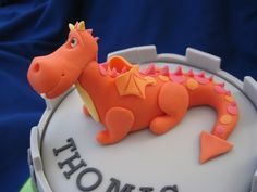 a birthday cake decorated with an orange dragon on it's side and the words happy birthday written in large letters