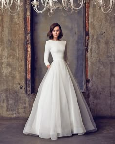 a woman in a white wedding dress standing next to a chandelier