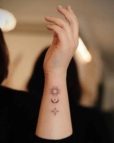 a woman's wrist with a small sun and moon tattoo on her left arm