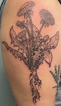 a woman's thigh with flowers and leaves on her leg, in black ink