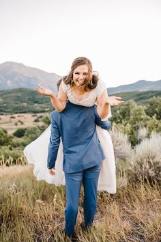 a bride carrying her groom on his back in the mountains at their outdoor wedding ceremony