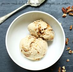 two scoops of ice cream in a white bowl with pecans on the side