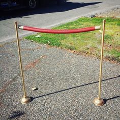 a red and gold metal pole with two poles on the ground next to some grass