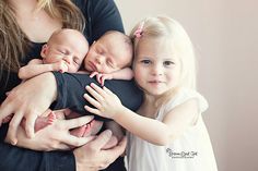 a woman holding three babies in her arms