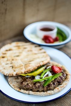 two plates with pita bread on them and some vegetables in the middle one plate is filled with meat