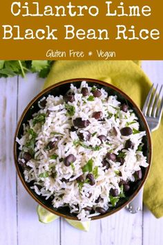 a bowl filled with rice, beans and cilantro on top of a wooden table