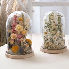 two snow globes with flowers in them sitting on a table next to each other