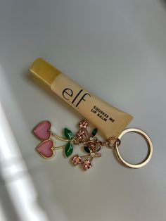 a tube of foundation next to a keychain with charms on it and a ring