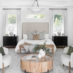 a bedroom with white walls and wooden furniture in the center, along with two windows