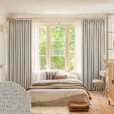 a bed sitting under a window next to a wooden dresser in a room with white walls