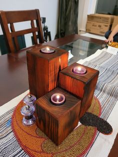 three candles are sitting on top of some wood blocks and one candle is lit in the middle