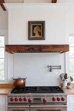 a stove top oven sitting inside of a kitchen next to a painting on the wall