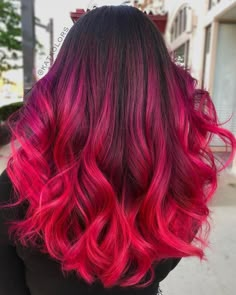 the back of a woman's head with red and pink hair in front of her