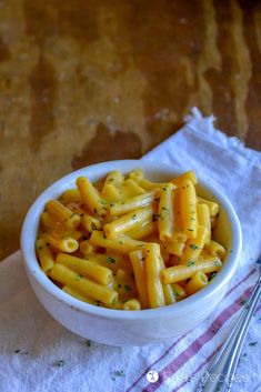 a white bowl filled with macaroni and cheese on top of a table next to a