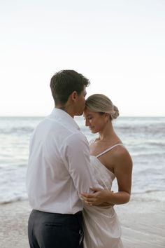 a man and woman standing next to each other on a beach