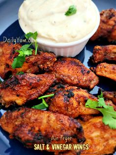 grilled chicken wings with tartar sauce and parsley garnish on a blue plate