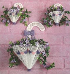 three white umbrellas with purple flowers hanging on a brick wall next to each other