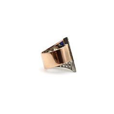 This is part of Chairish’s Fine Jewelry assortment.  The spectacular design of this 14k gold and platinum ring is on the cusp of the Art Deco and Retro eras; the influence of both eras makes this ring bold and unique. The ring’s shape is a geometric dynamic swath—both rhythmic and ribbonlike. A large (1.15 carat) Old European cut diamond is the centerpiece of the ring, with a smaller diamond placed next to it. Below it, a row of channel set square-cut sapphires add L-shape delineation. The final Art Deco 14k Gold Rings With Diamond Accents, Art Deco Multi-stone Ring For Formal Occasions, Art Deco Baguette Cut Ring For Formal Occasions, Art Deco Rose Gold Diamond Ring, Luxury 14k Gold Evening Ring, Antique Wide Band Jewelry For Formal Occasions, Art Deco Rose Gold Rings For Formal Occasions, Evening Rings With Diamond Accents In 14k Gold, Formal Art Deco Baguette Cut Ring