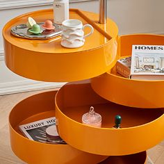 an orange coffee table with magazines and cups on the trays in front of it