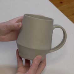 a hand holding a coffee mug on top of a table