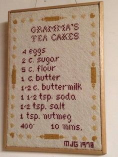 a cross stitch sample hanging on the wall in front of a sign that says grandma's ten cakes