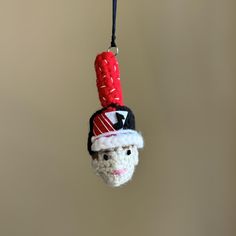 a crocheted christmas ornament hanging from a string with a santa hat on it