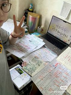 a young boy sitting at a desk with lots of papers and writing on the table