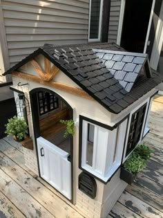 a dog house built into the side of a wooden deck with potted plants on it