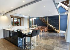 an open kitchen and living room with stairs leading up to the second floor in this modern home