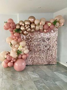 balloons and greenery are arranged on the floor in front of a large pink wall