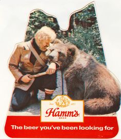 an old man sitting next to a bear with a beer bottle in it's mouth