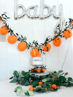 an orange themed baby shower with balloons and greenery