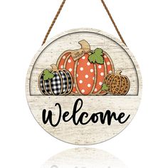 a welcome sign hanging from a rope with pumpkins and other fall decorations on it