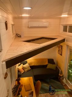 the interior of a tiny house with a couch and table in front of an air conditioner