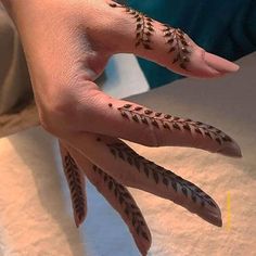 a woman's hand with hennap on it and two fingers that have leaves painted on them