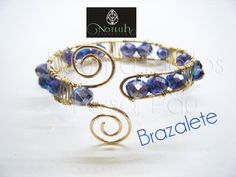 a bracelet made out of wire with blue beads and gold spirals on the end