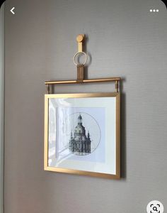 a photo hanging on the wall with a gold frame and metal ring in front of it