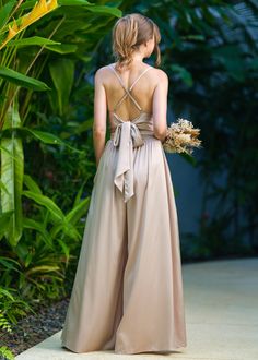 a woman in a long dress is walking down the street with her back to the camera