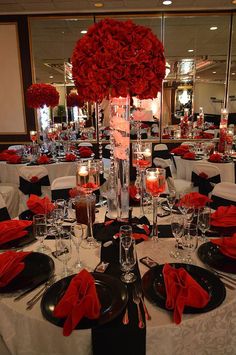 a table set with black and white plates, red napkins, silverware and candles