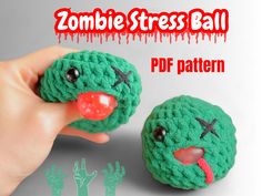 a hand holding a green crocheted zombie ball