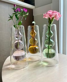 three vases with flowers in them sitting on a table