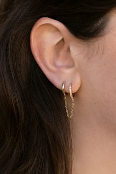 Invoke some serious ear party envy with the Elliott Double Hoops. Two huggies, one encrusted with CZs, connected by a dainty chain–your double piercings will thank you. STYLING TIP: Top off the look with the MF classic, Josette Ear Cuff. No additional piercing needed. 18k gold-plated brass 2 - 13mm hoops, 1 plain and 1 pave 1.5mm connecting chain width **Must have double piercing Double Piercing Earrings Gold, 2nd Ear Piercing, Double Piercing, Ear Party, Dainty Chain, Pendant Bracelet, Chain Pendants, Chain Bracelet, Ear Piercings