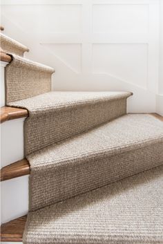 a carpeted staircase with white walls and wooden handrails