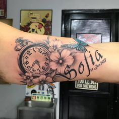 a woman's arm with a clock and flowers on it