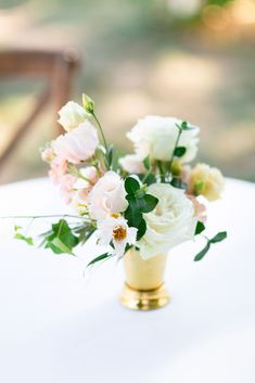 white and pink flowers in a gold vase on a table